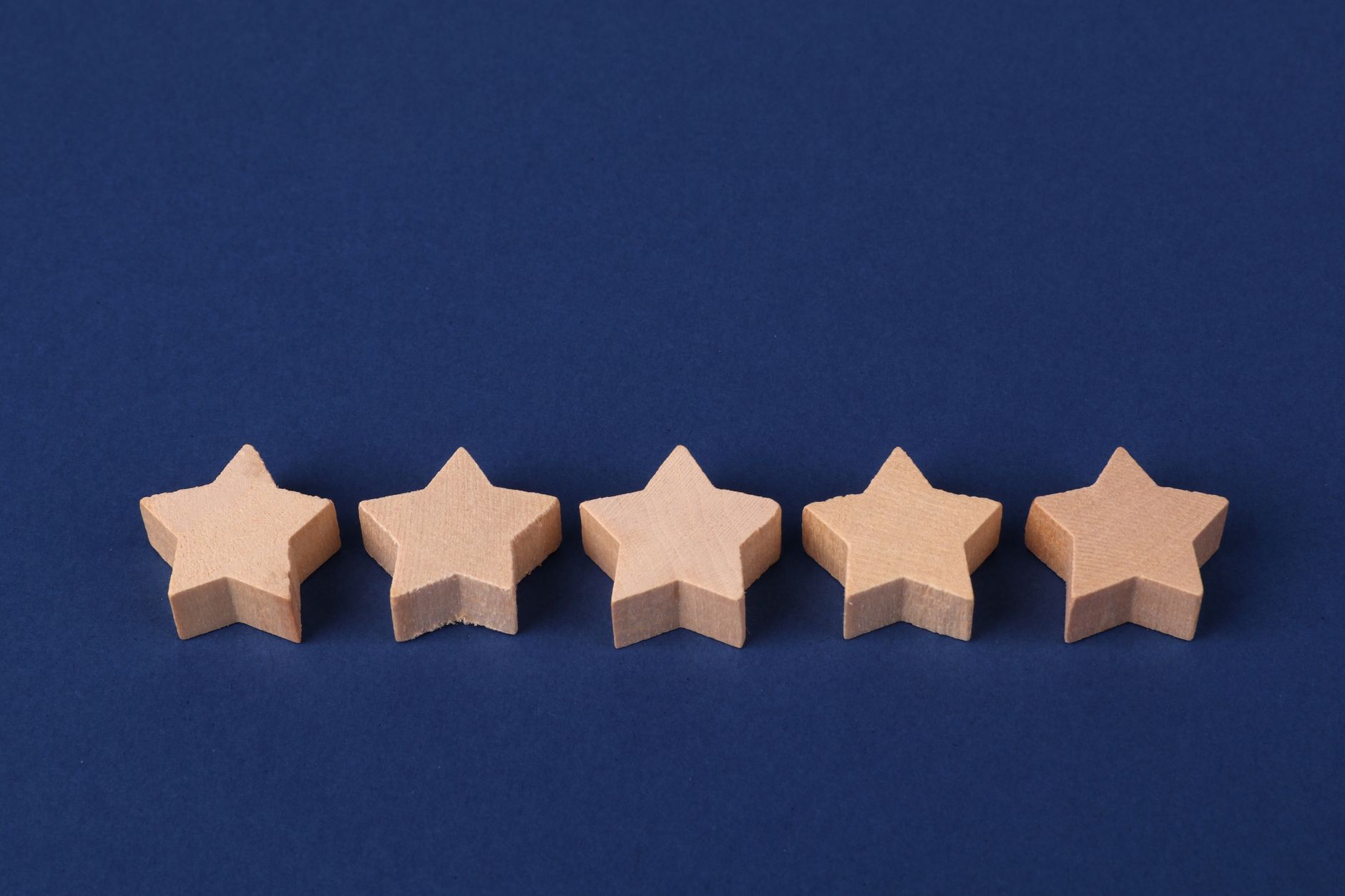 Five wooden stars on a blue background representing a rating system or evaluation concept.